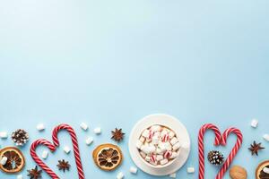 Cup of hot chocolate with marshmallow cocoa powder and caramel nuts, oranges on pastel blue background with copy space. Christmas winter concept. photo