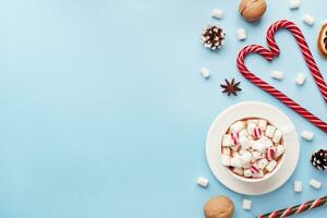 Cup of hot chocolate with marshmallow cocoa powder and caramel nuts, oranges on pastel blue background with copy space. Christmas winter concept. photo