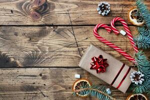 Gift box with bow. Christmas tree and decorations, cane caramel and oranges nuts Wooden background copy space. photo