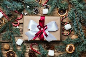 Gift box with bow. Christmas tree and decorations, cane caramel and oranges nuts Wooden background photo