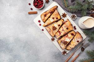 Cottage cheese pie casserole with cranberries and spices sprinkled with powdered sugar on a wooden stand. Gray concrete table. Copy space photo