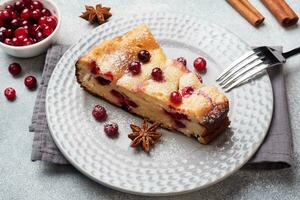 A piece of cottage cheese pie casserole with cranberry berries and spices cinnamon and anise on a plate. Grey concrete background. photo