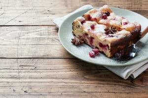 Two pieces of cottage cheese pie casserole with cranberry berries and spices cinnamon and anise on a plate. Wooden background. Copy space. photo