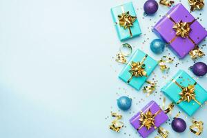 Flat lay background for celebration Christmas and New Year. Gift boxes are purple and turquoise with gold ribbons bows and confetti stars on a blue background. top view copy space. photo