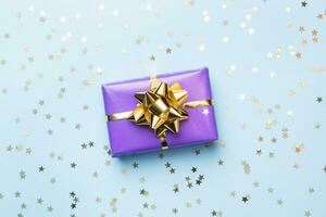 Flat lay background for celebration Christmas and New Year. Gift boxes are purple with gold ribbons bows and confetti stars on a blue background. top view copy space. photo