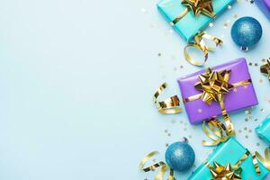 Flat lay background for celebration Christmas and New Year. Gift boxes are purple and turquoise with gold ribbons bows and confetti stars on a blue background. top view copy space. photo