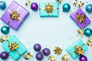 Flat lay background for celebration Christmas and New Year. Gift boxes are purple and turquoise with gold ribbons bows and confetti stars on a blue background. top view copy space. photo