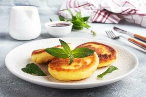 buñuelos de cabaña queso con menta. queso Cuajada pasteles de queso, panqueques en un gris hormigón antecedentes foto