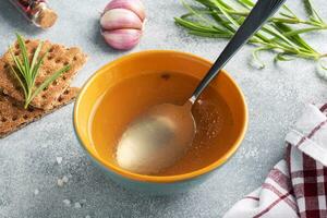 Boiled meat broth in a plate with spices garlic and rosemary. photo