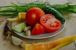 Vegetables and herbs, preparation for salad, are on a plate photo