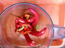 un licuadora lleno con rojo pimientos y verde pimientos foto