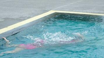 Child jumping in swimming pool, water splashing. Children in swimming pool having fun during family summer vacation. video