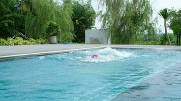 Child jumping in swimming pool, water splashing. Children in swimming pool having fun during family summer vacation. video