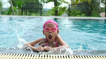 bonito pequeño niña nadando y jugando en agua. niños en nadando piscina teniendo divertido durante familia verano vacaciones. video