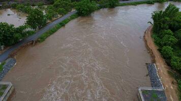 antenn se av vatten släppte från de dränering kanal av de betong damm är en sätt av överfyllda vatten i de regnig säsong. topp se av grumlig brun skog vatten flöden från en damm i thailand. video