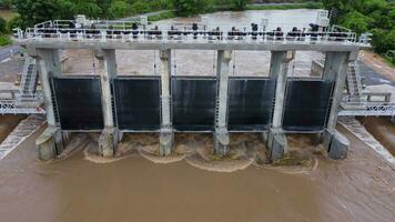 vue aérienne de l'eau libérée du canal de drainage du barrage en béton est un moyen de déborder de l'eau pendant la saison des pluies. vue de dessus de l'eau de la forêt brune trouble s'écoule d'un barrage en thaïlande. video