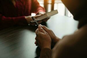 Two people reading and study bible in home and pray together.Studying the Word Of God With Friends. in sun light photo