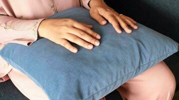 women holding a orange color pillow while sit on a sofa , video