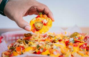 cerca arriba de mano de tomando nachos en aislado antecedentes. mano tomando y demostración un nacho aislado foto