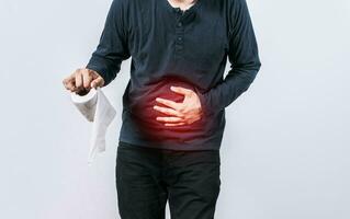 Person with toilet paper with stomach problems on isolated background, Concept of a person with digestive and diarrhea problems, Man with stomach problems holding toilet paper photo