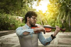 Portrait of man playing violin at sunset. Close up of violinist man playing in the street. Violinist artist playing a melody outdoors, Image of a person playing the violin outdoors photo