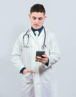 Handsome doctor using phone on isolated background. Young latin doctor holding telephone isolated photo