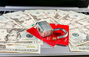 Close up of Padlock on top of credit card on dollar bills, Concept of credit card information theft. Padlock with credit card on top of dollars photo