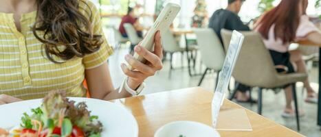 Woman use smartphone to scan QR code to pay in cafe restaurant with a digital payment without cash. Choose menu and order accumulate discount. E wallet, technology, pay online, credit card, bank app. photo