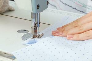 Female hands of a master tailor at work, a sewing machine needle photo