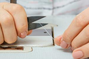 Female hands of a master tailor cuts a thread with scissors photo