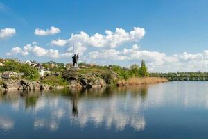 green coast of a beautiful small river with white clouds in reflection photo