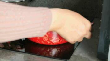 women hand putting cooking pan on electric stove, electric stove is heated to red. video