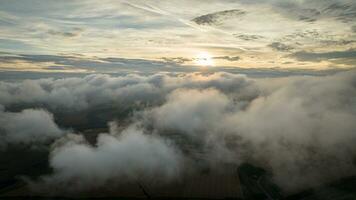 aéreo ver de un nublado puesta de sol mientras volador encima el nubes foto