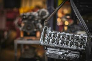 Cylinder head repaired waiting to go on an engine block in background photo