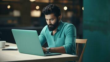 Handsome bearded man using laptop while sitting at table in cafe photo