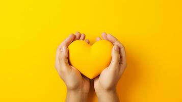 hands holding yellow heart on yellow background photo