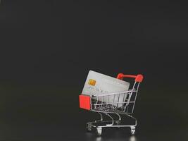 shopping cart or trolley and credit card   isolated  on black  background . photo
