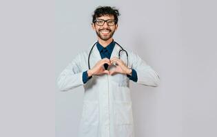 joven médico haciendo corazón forma aislado. hermoso médico haciendo corazón gesto con manos. contento médico señalando dedos abajo foto