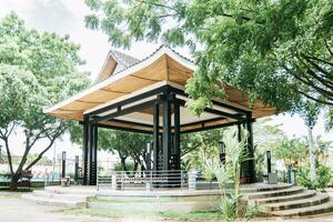 un Estilo chino quiosco rodeado por árboles, un parque con un Estilo japones quiosco, concepto de un pequeño japonés templo foto