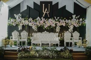 a wedding stage with white chairs and flowers photo