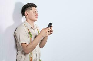Handsome guy happy with his cell phone on isolated backgrounds, young latin man happy with his cell phone isolated, man on white background texting with his cell phone photo