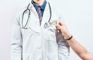 Medical bribery concept. Hand of person bribing doctor, Hands putting money in doctor pocket photo