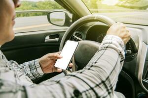 Man using his phone while driving, Person holding the cell phone and with the other hand the steering wheel, Concept of irresponsible driving, Distracted driver using the cell phone while driving photo