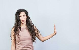 Displeased young woman rejecting with palm of hand isolated. Displeased girl making rejection gesture with palm of hand on white background. photo