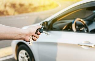 Driver hands showing the keys outside the vehicle, Vehicle rental concept. Close-up of driver outside car holding keys. Driver hands showing the car keys photo