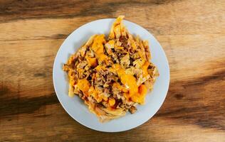 Top view of chicken nachos with melted cheese. Plate of chicken nachos with melted cheese on wooden table photo
