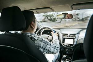 Back view of a man driving a car, Man's hands on the wheel of the car, inside view of a man driving a car, Concept of hands on the wheel of a car photo