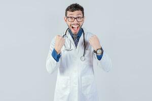 Handsome excited doctor celebrating a victory on white background. Young happy doctor celebrating something isolated photo