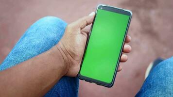 young man using smart phone while sitting on park bench video