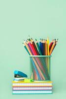 Colored pencils in jar with notebooks and school supplies. Back to school concept photo